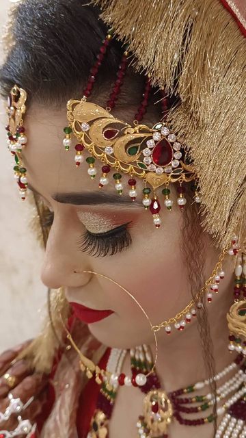 a woman wearing a red and gold costume with feathers on her head, holding beads around her neck