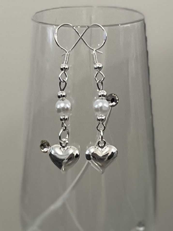 Silver pearl heart earrings. Free glass charm with every order. Add a touch of elegance to your wardrobe with these timeless heart earrings. Handcrafted with love to elevate any look or outfit. Sterling silver ear hook with a single faux pearl and heart dangle drop. Hypoallergic. Free shipping to UK buyers. Dispatched within 1-3 days but I aim for next day postage or if ordered before 12 the same day.  Presented on a gift card and wrapped beautifully in luxury tissue paper and a blush pink organza bag making this the perfect gift for loved ones.  If you are not completely in LOVE with your purchase, please let me know and you'll receive a stress free refund. Customer satisfaction is my main priority. These are perfect for any occasion but perfect for a bride or as bridesmaid jewellery or g Elegant Heart Pendant Earrings For Weddings, Silver Heart Beads Jewelry For Wedding, Elegant Silver Earrings With Heart Charm, Silver Heart Pendant Earrings For Wedding, Dainty Double Heart Earrings For Wedding, Teardrop Heart Charm Earrings For Wedding, Sterling Silver Dangle Heart Earrings For Party, Sterling Silver Heart Drop Earrings For Party, White Heart Earrings For Wedding On Valentine's Day