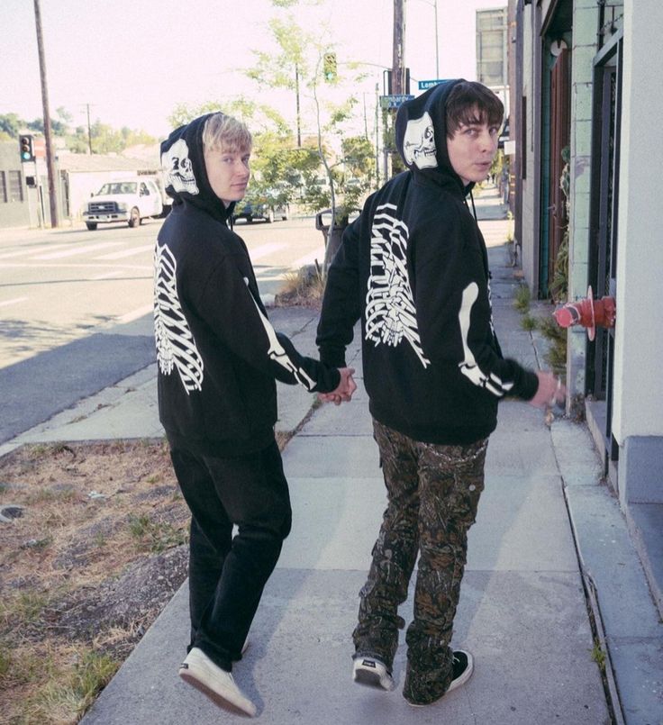 two young men walking down a sidewalk with skeleton hoodies on their heads and feet