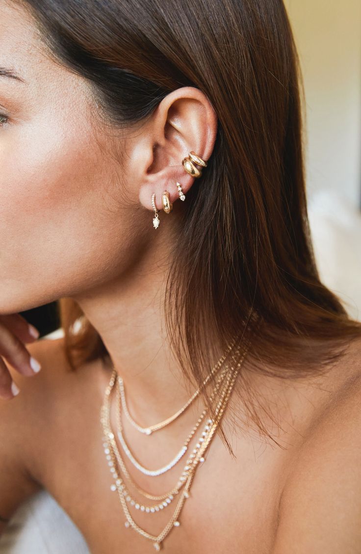 a close up of a person wearing ear rings and necklaces with pearls on them