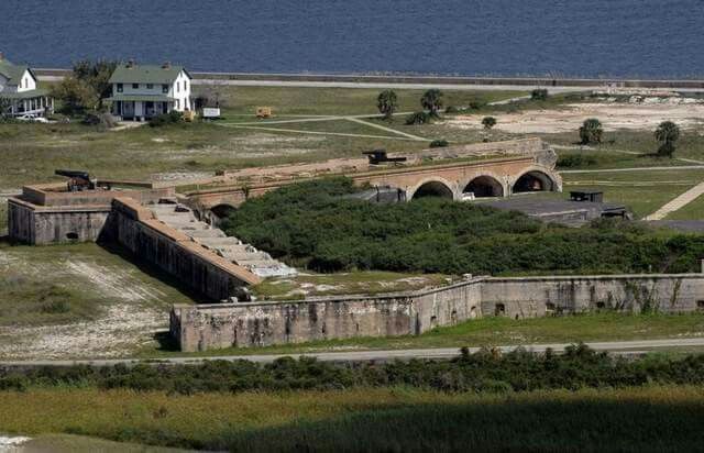 an aerial view of the old fort and surrounding buildings, with water in the background