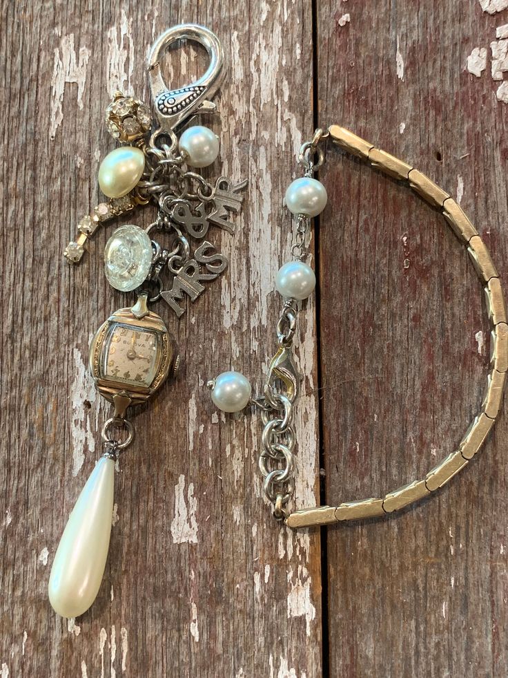 a close up of a bracelet on a wooden surface with pearls and charms hanging from it