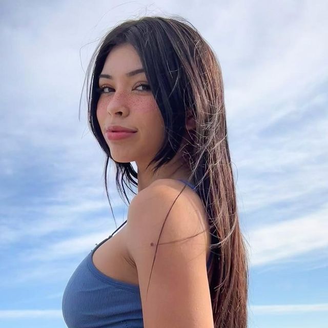 a woman with long hair standing on the beach