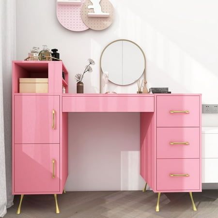 a pink desk with gold handles and drawers in front of a wall mounted round mirror