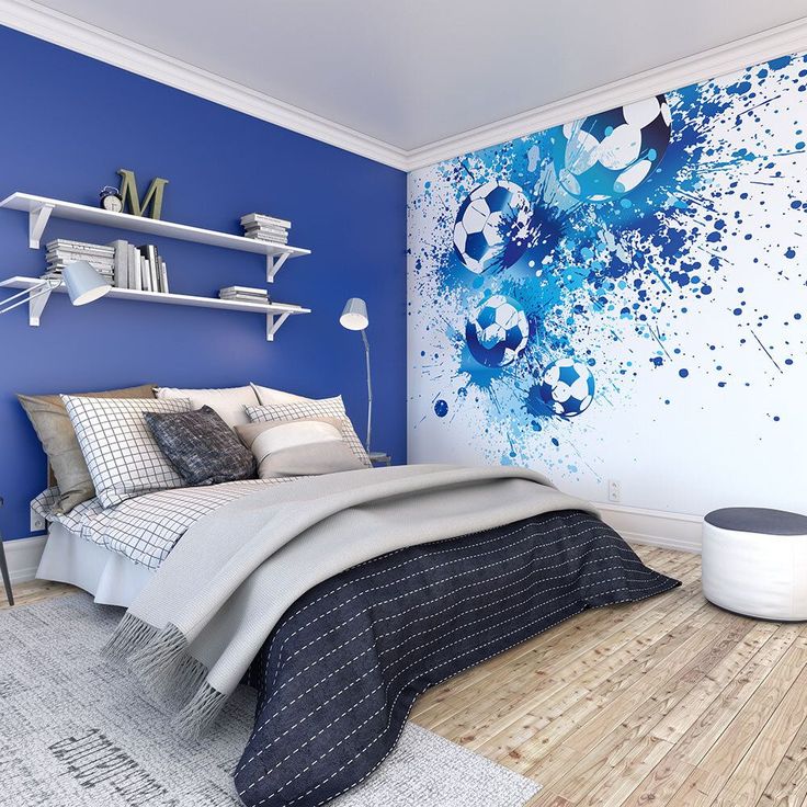 a bedroom painted in blue and white with soccer balls on the wall behind the bed