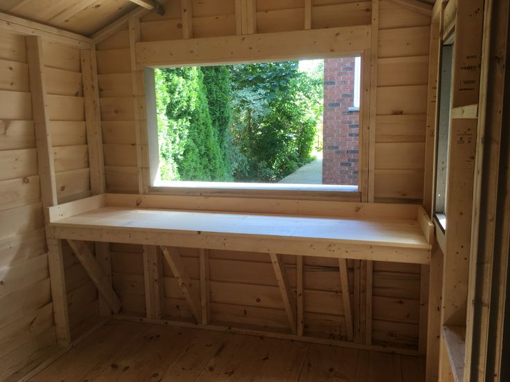 an empty wooden room with a window and bench