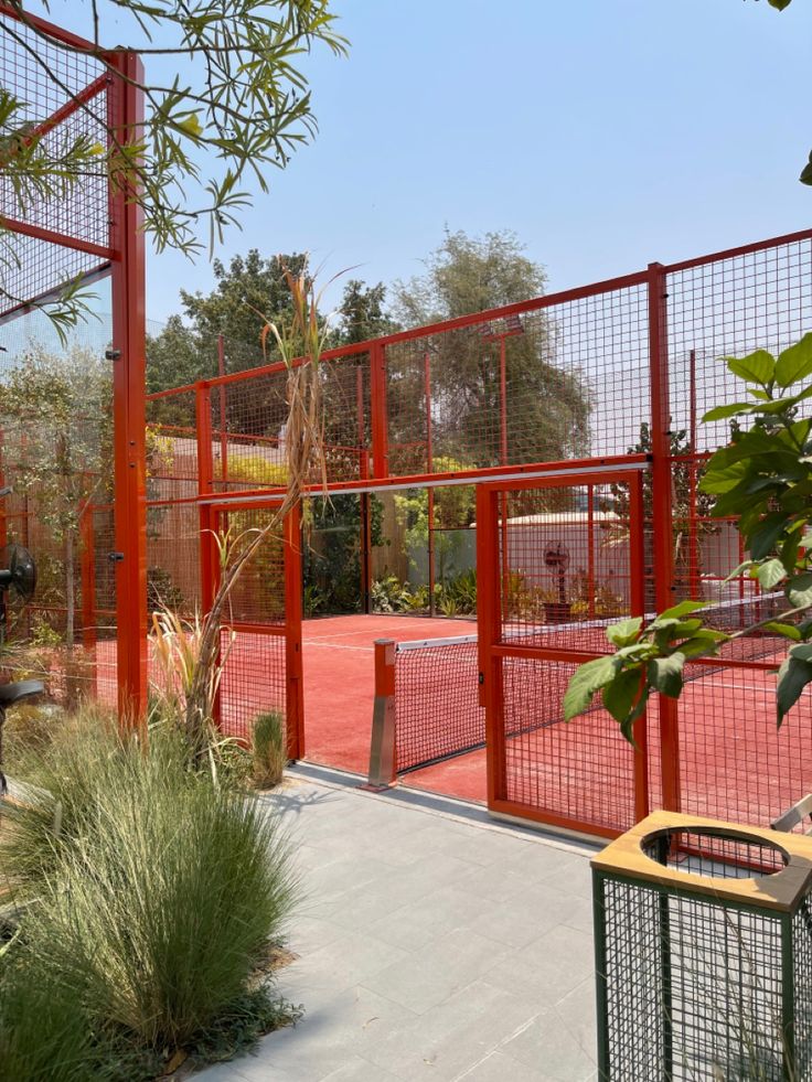 an outdoor tennis court surrounded by plants and trees