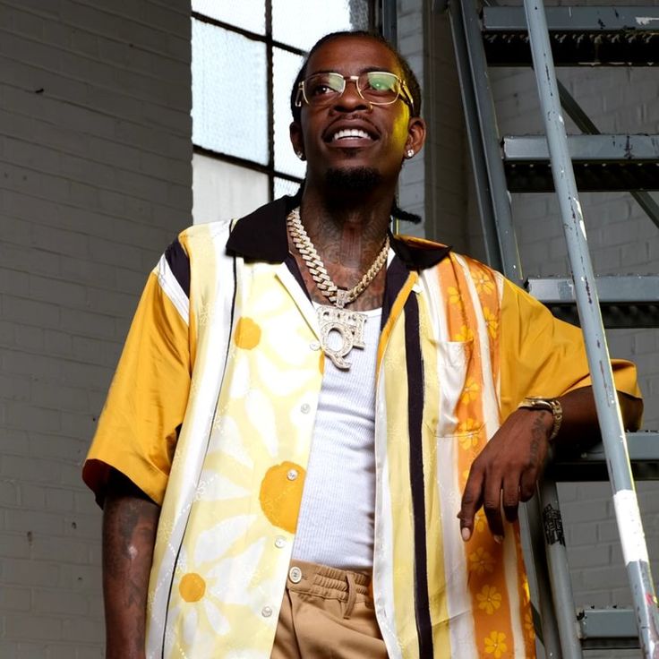 a man standing next to a ladder wearing sunglasses and a yellow shirt with sunflowers on it