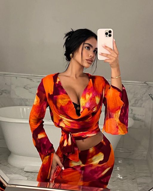 a woman taking a selfie in front of a toilet with her cell phone up to her ear