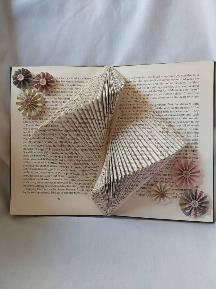 an open book with paper flowers on it