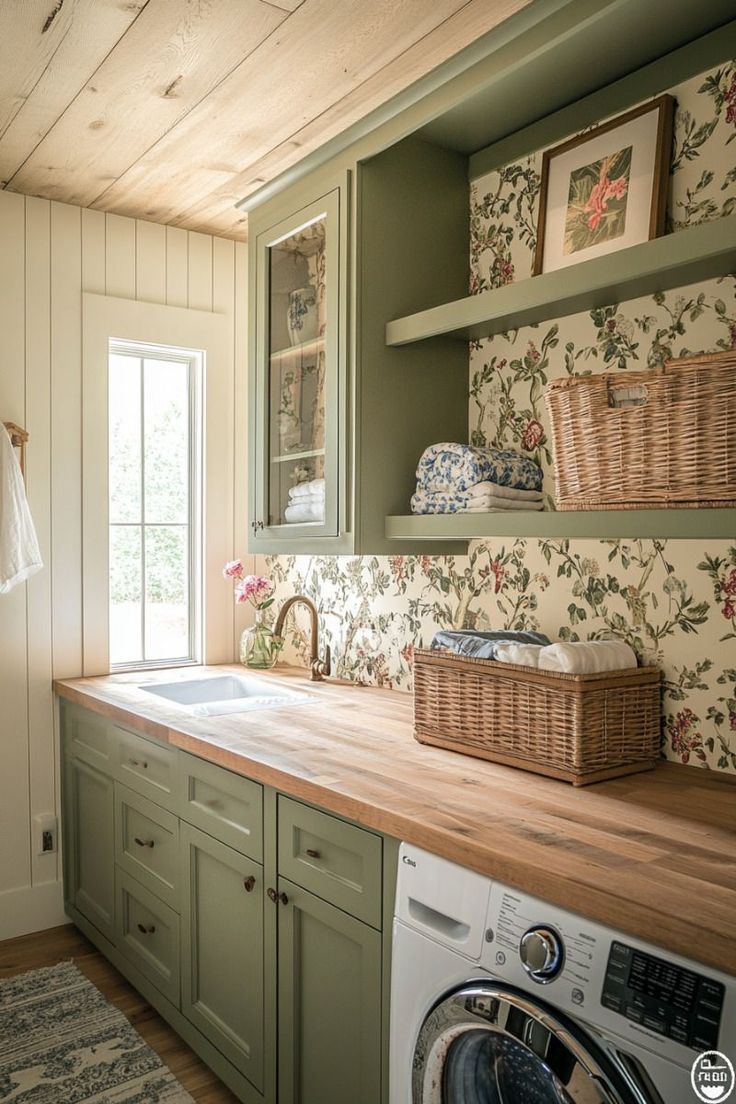 a washer and dryer in a small room with green cabinets, wood counter tops and floral wallpaper