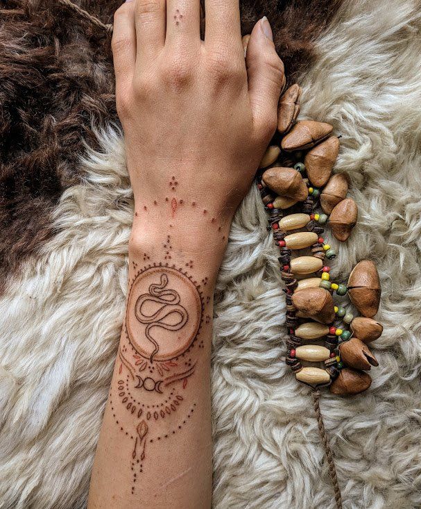 a woman's hand with a tattoo on her wrist and some nuts in the background