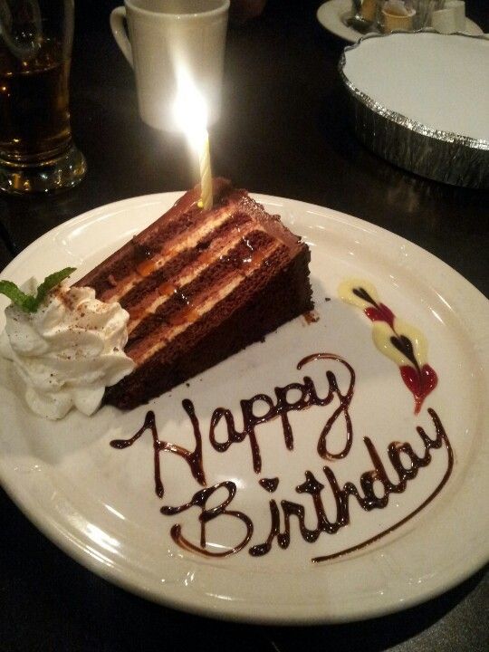 a piece of birthday cake on a plate with a lit candle