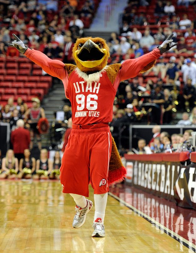 the mascot is running down the court at a basketball game with his arms in the air