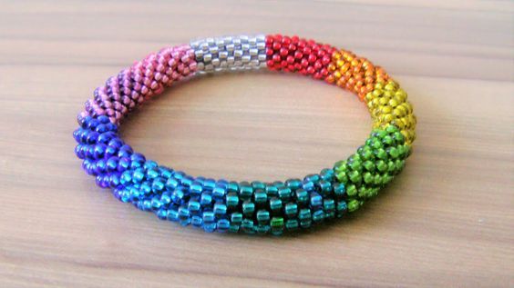 multicolored beaded bracelets sitting on top of a wooden table