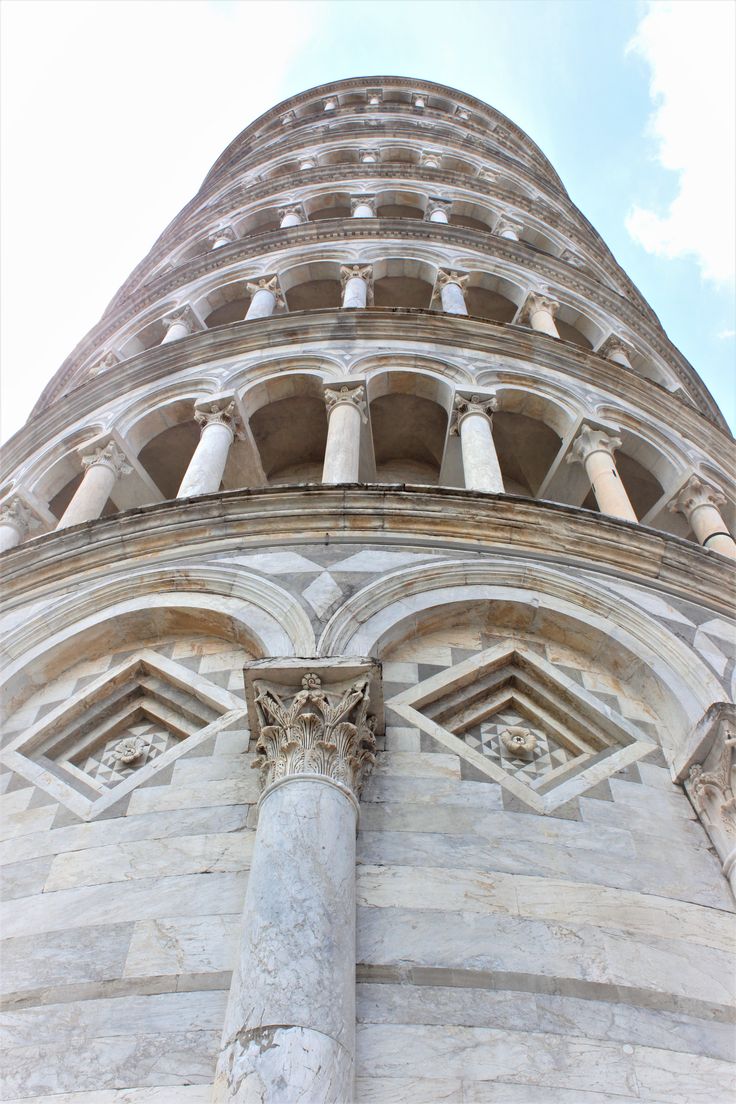 the top of a tall building with statues on it's sides and columns below