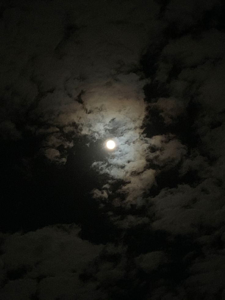 the moon is shining brightly in the dark sky with clouds all around it and on its side