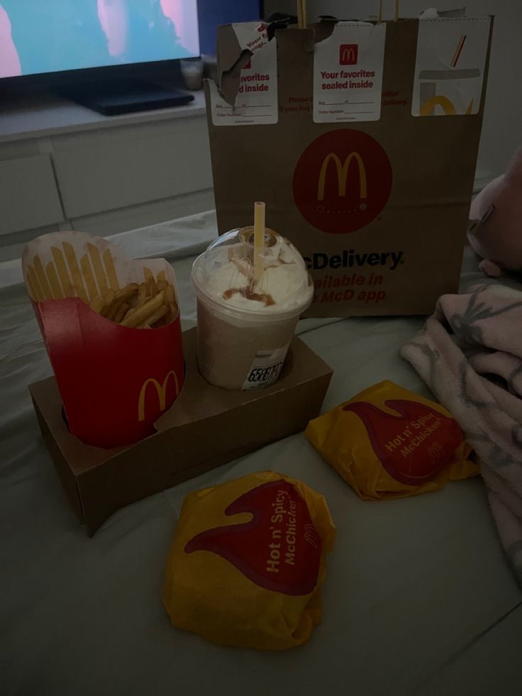 a table topped with boxes filled with food next to a flat screen tv on top of a bed