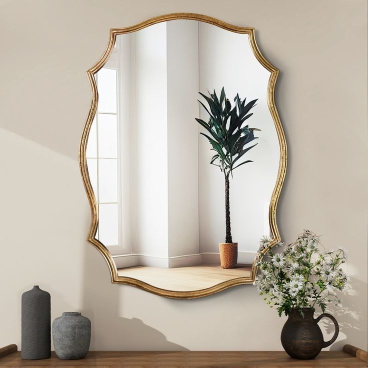 a mirror sitting on top of a wooden table next to a vase with a plant