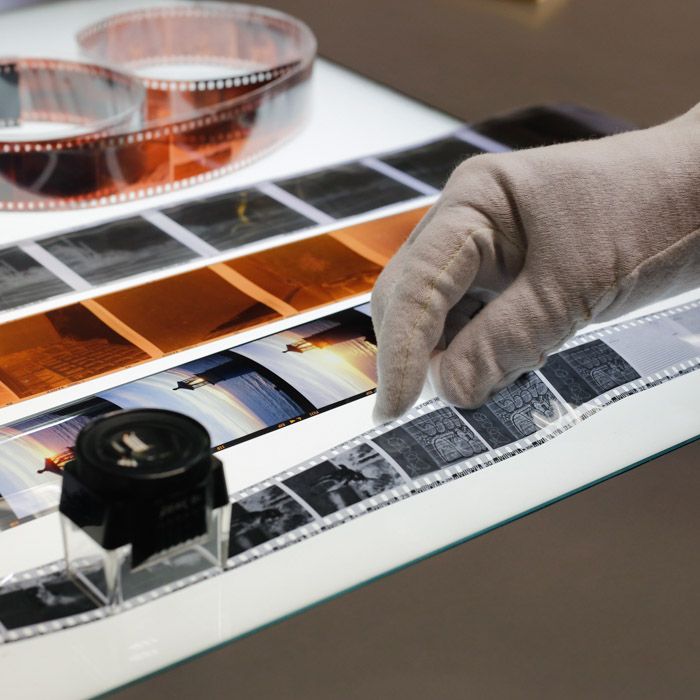 a person's hand is pointing at some film strips on a table with other films