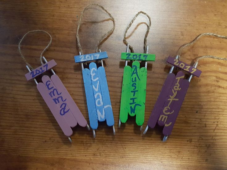 four wooden clothes pins with name tags on them sitting on top of a wood table