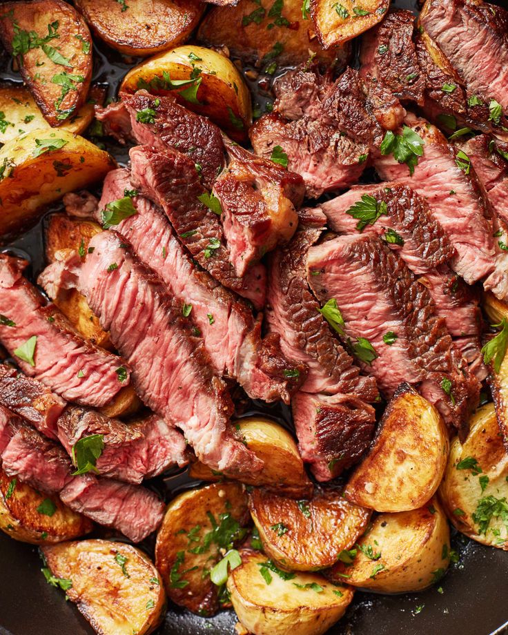 steak and potatoes in a skillet with parsley on the side, ready to be eaten