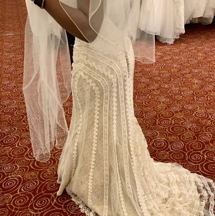 a woman in a white wedding dress is looking at her cell phone while wearing a veil