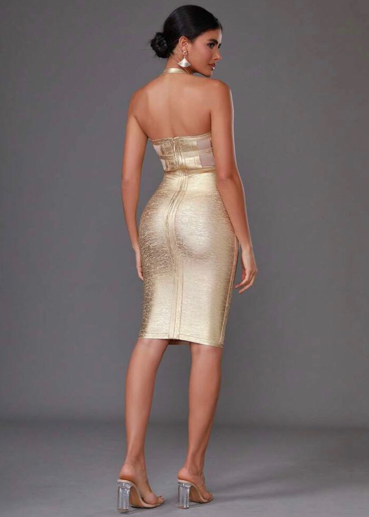 a woman wearing a gold dress with high heels on the side and her back to the camera