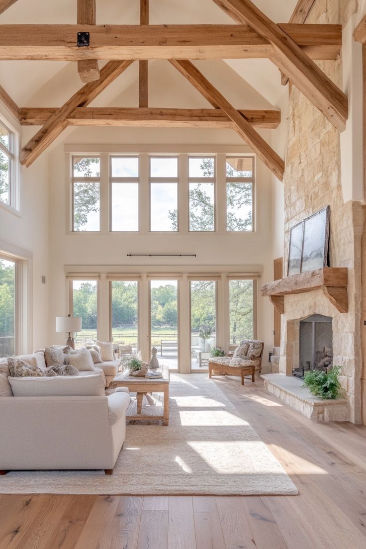 a large open living room with high ceilings and wood beams on the ceiling is filled with furniture