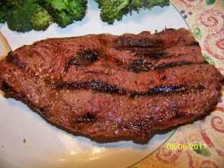 a steak and broccoli on a white plate with a paisley table cloth in the background