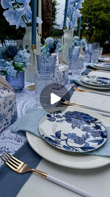 the table is set with blue and white plates, silverware, and napkins