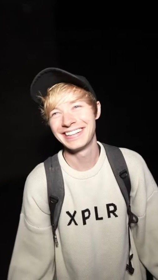 a man with suspenders and a hat smiles at the camera while wearing a sweatshirt that says you'll always be a xpplr