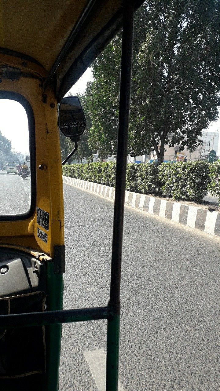 a view from the back seat of a small vehicle on a road with trees in the background