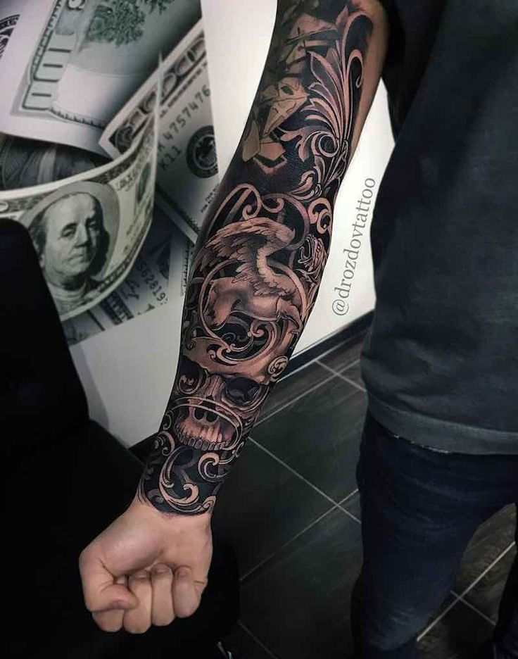 a man with a black and grey tattoo on his arm next to a stack of money