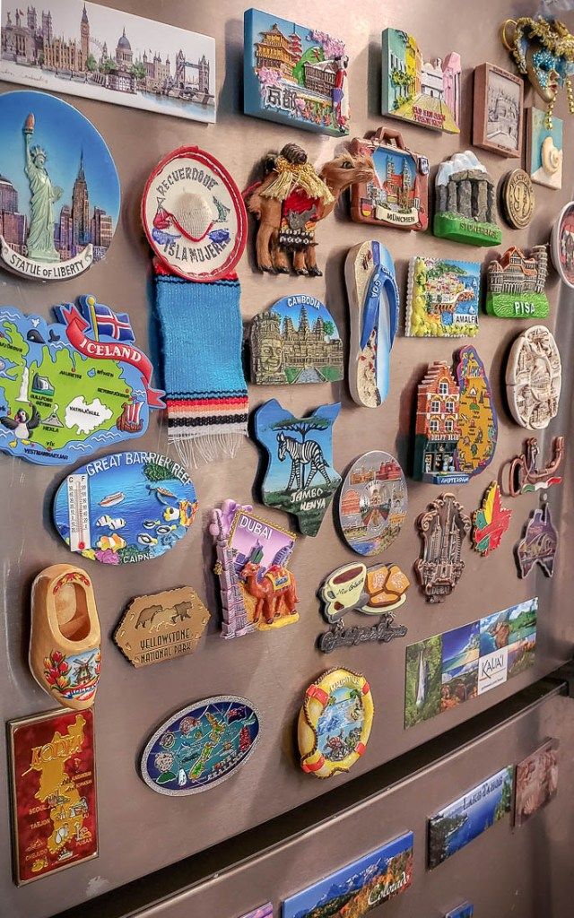 a refrigerator covered in magnets with pictures on the front and bottom panel, including cities