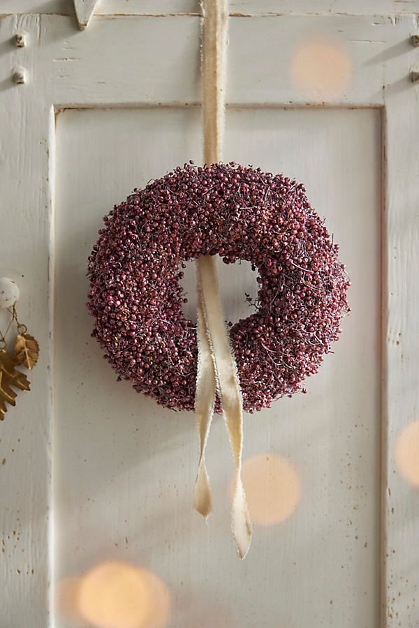 a door with a wreath hanging from it's side and lights in the background