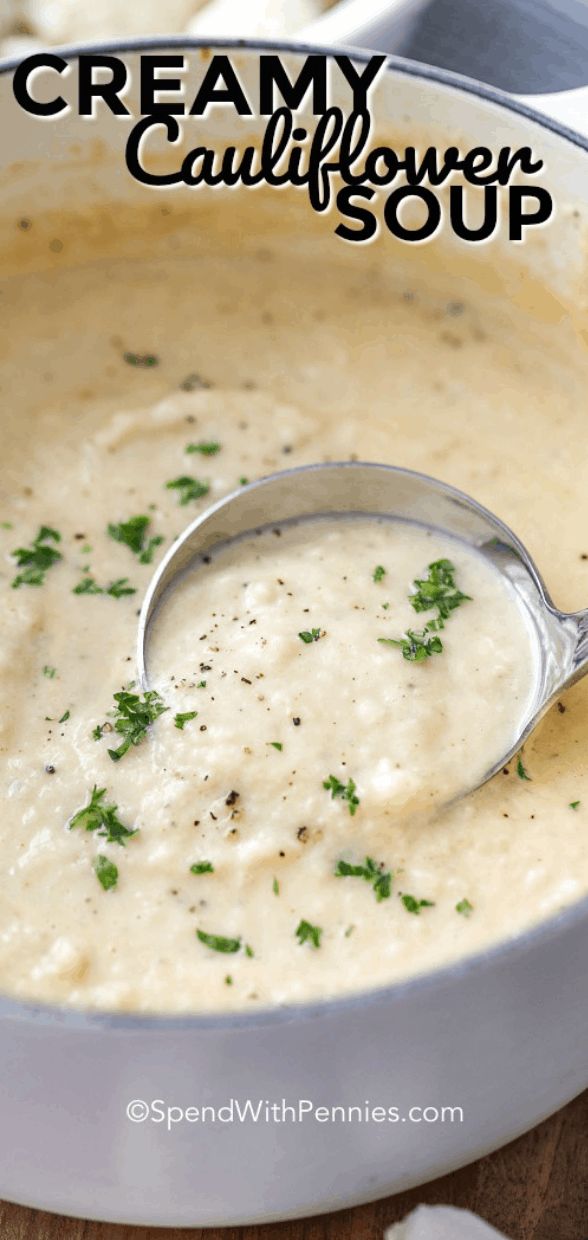 creamy cauliflower soup in a white bowl with a spoon