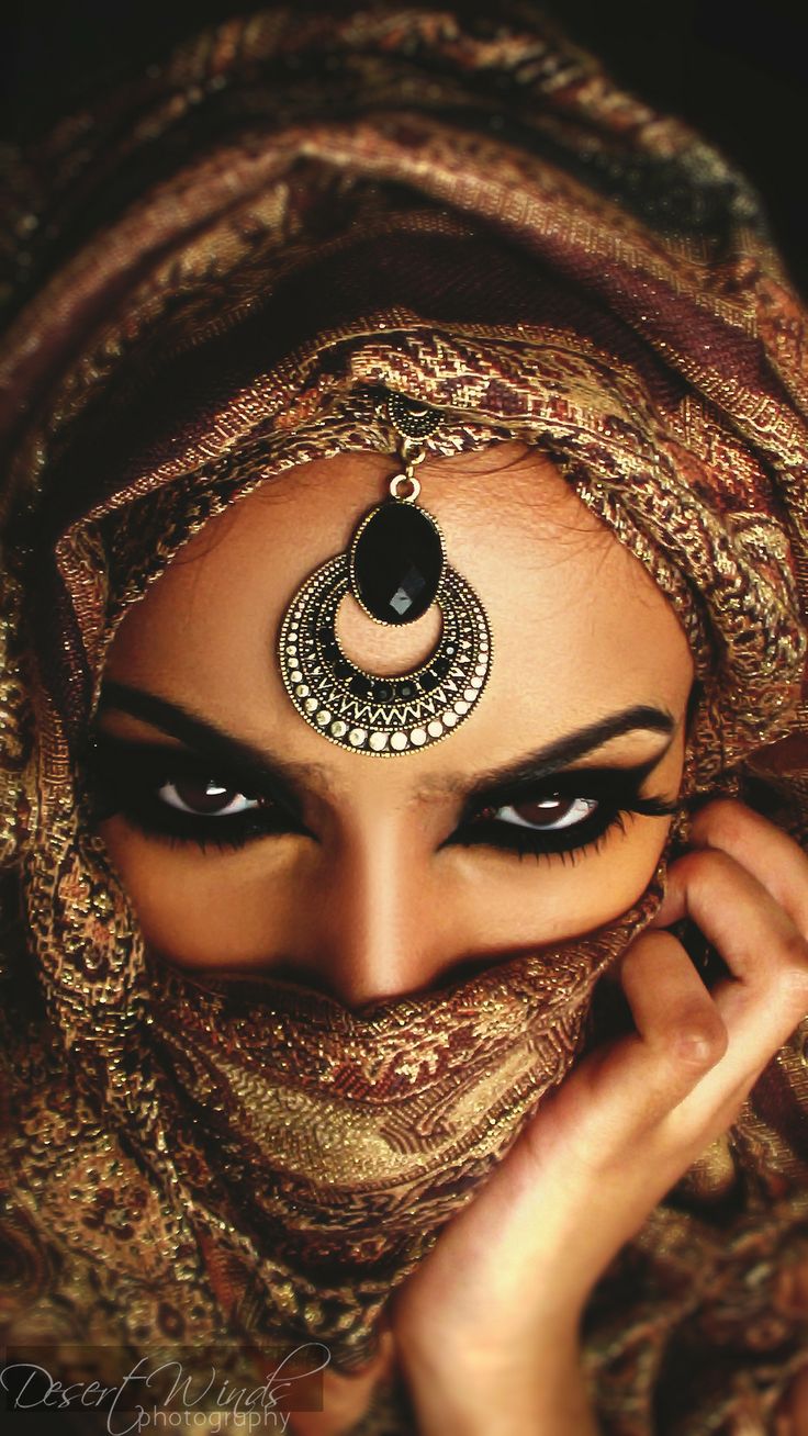 a woman wearing a head scarf and black eyeliners is posing for the camera