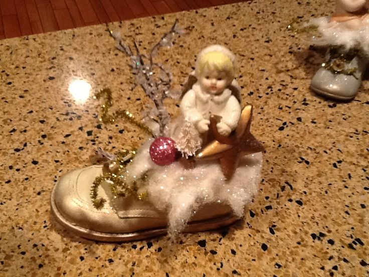 a small figurine sitting on top of a shoe next to a christmas tree