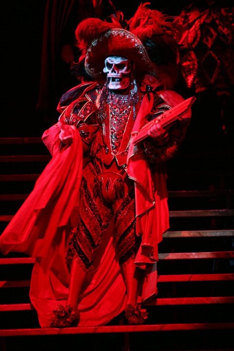 a man dressed in red and black with a skull on his face wearing a costume