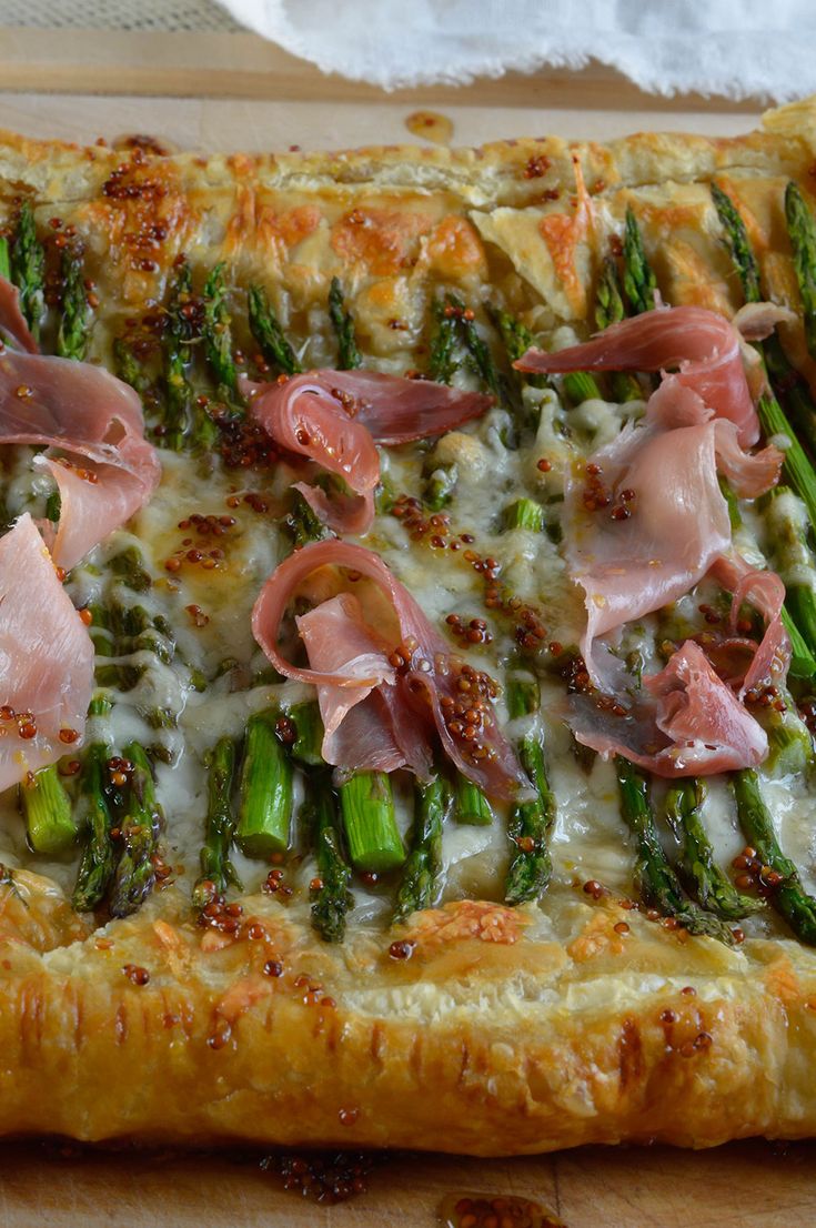 a pizza with asparagus, ham and cheese on it