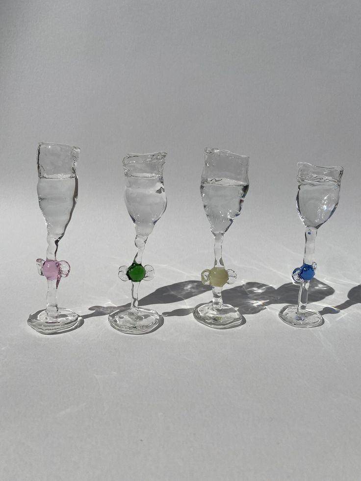 five wine glasses are lined up on a white surface with one empty glass in the middle