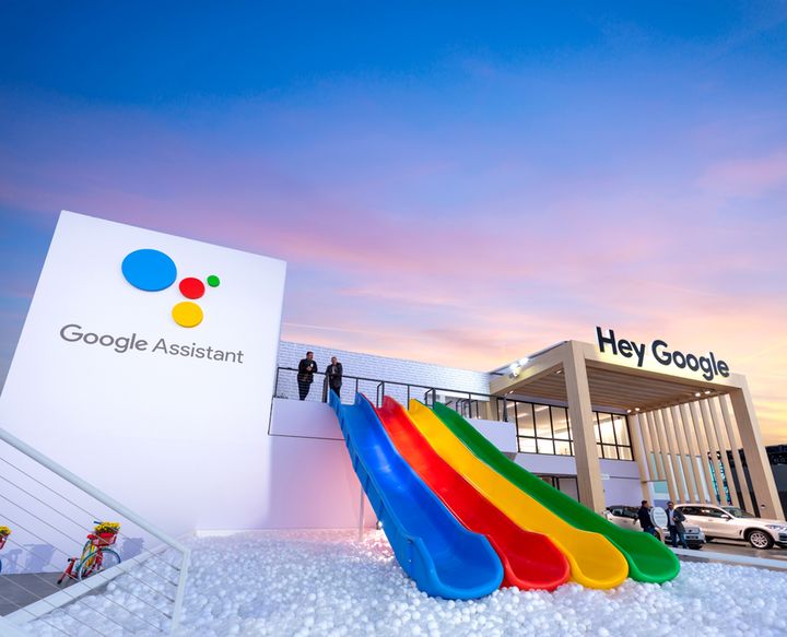 the google assistant sign is displayed in front of an office building with rainbow - colored umbrellas