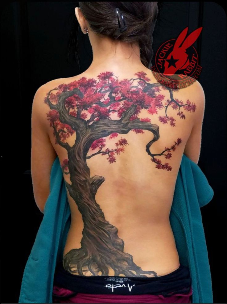 the back of a woman's body is covered in tattoos with red flowers on it