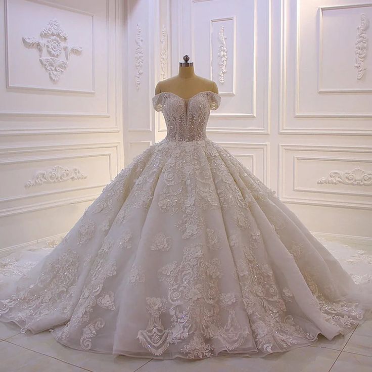 a wedding dress on display in a white room