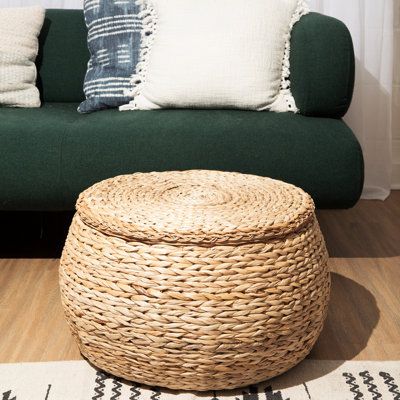 a living room with a green couch and wicker basket on the floor next to it