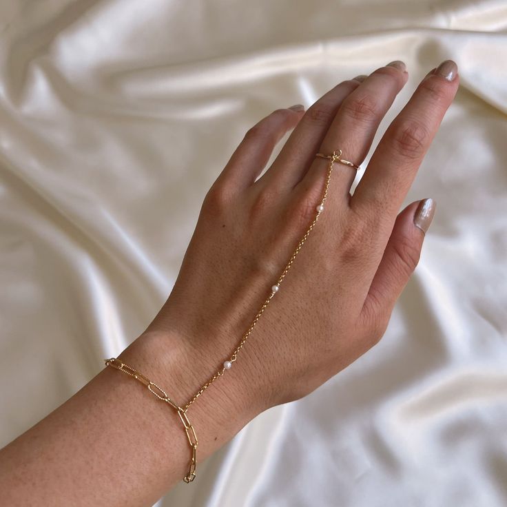 14k gold filled paperclip chain with freshwater pearl detailing connected to plain stacking ring Please select your preferred ring size, bracelet size, and connection piece size. Please note that bracelet comes with a 1" extension chain To measure connection piece, lay your hand flat and measure from the bottom of your finger to where you want your bracelet to lay. Model is wearing a 4.5" connector. If you wish to have a size other than the options listed, please email keikojewelry@gmail.com or leave a note at checkout. Processing Time: Each piece is made to order & takes approximately 10-14 business days to ship. If you do need your order sooner, please select the "RUSH MY ORDER" add on for an additional fee. *Rush orders must be discussed and approved prior to purchase to ensure appropri Bracelet Connected To Ring, Ring To Bracelet Jewellery, Ring And Bracelet Connected, Bracelet Ring Chain, Finger Ring Bracelet, Christmas Basket, Hand Chain Bracelet, Ring Bracelet Chain, Freshwater Pearl Ring