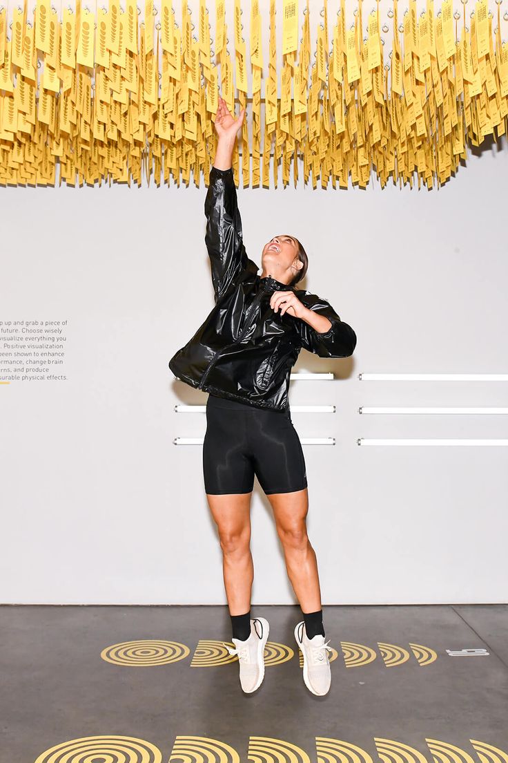 a woman standing in front of a wall with yellow streamers hanging from the ceiling