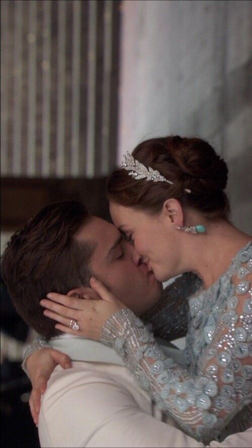 a man and woman kissing each other while wearing tiaras