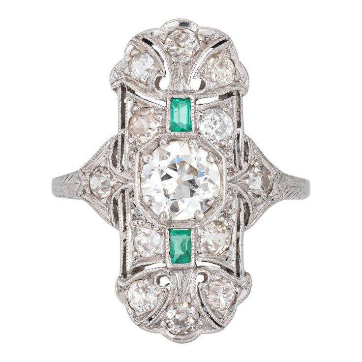 Finely detailed vintage Art Deco emerald & diamond ring (circa 1920s to 1930s) crafted in platinum.   Centre set old European cut diamond is estimated at .90 carats, accented with 12 estimated 0.05 carat old mine cut diamonds. The total diamond weight is estimated at 1.50 carats (estimated at I-J colour and VS2-SI2 clarity). Two emeralds total an estimated 0.10 carats. The emeralds are in good condition with a few nicks evident and general wear visible under a 10x loupe.    The elongated mount w Art Deco Emerald Diamond Ring With Accents, Art Deco Emerald Ring With Center Stone, Vintage Green Diamond Platinum Ring, Vintage Green Diamond Ring In Platinum, Vintage Emerald Ring With Diamond Accents, Heirloom Platinum Emerald Ring With 17 Jewels, Antique Emerald Diamond Ring With Brilliant Cut, Heirloom Emerald Ring With 17 Jewels In Platinum, Art Deco Emerald Ring With Platinum